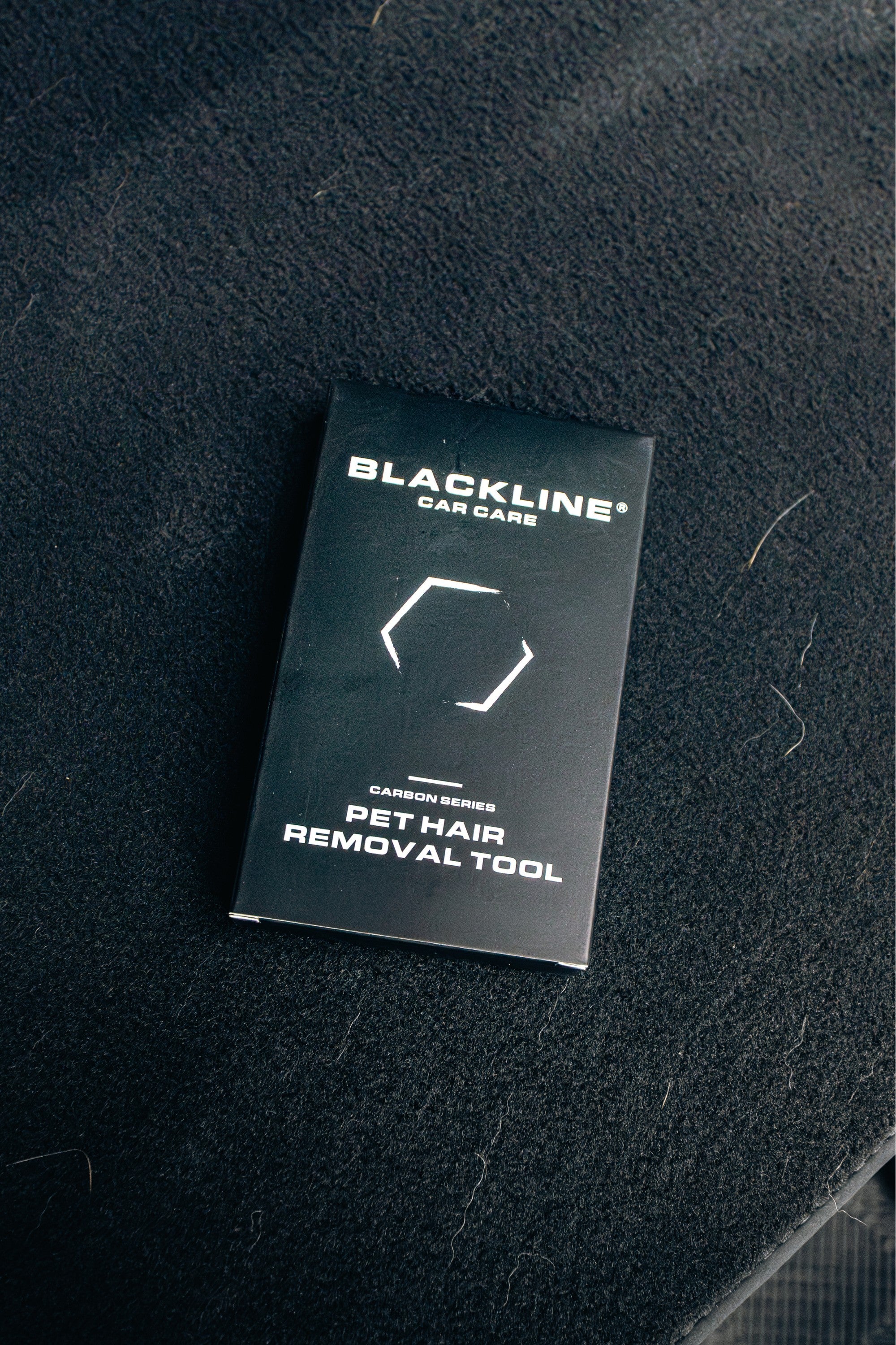 FurMidables BLACKLINE pet hair removal tool in black packaging on a carpeted surface for car interior cleaning