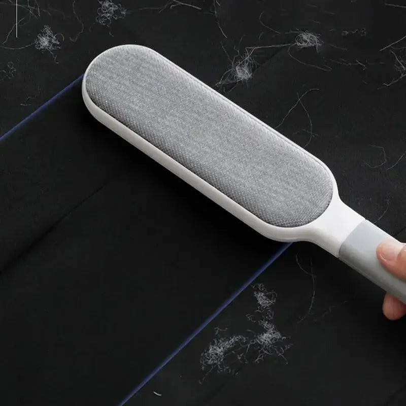 FurMidables double-sided electrostatic pet hair remover brush cleaning lint and fur from a black fabric surface